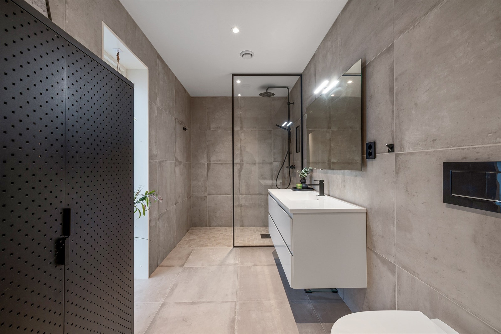 Badet har romslig walk-in dusj med sort glassramme, store fliser og vegghengt innredning som gir en stram, luftig atmosfære. Galleribilde