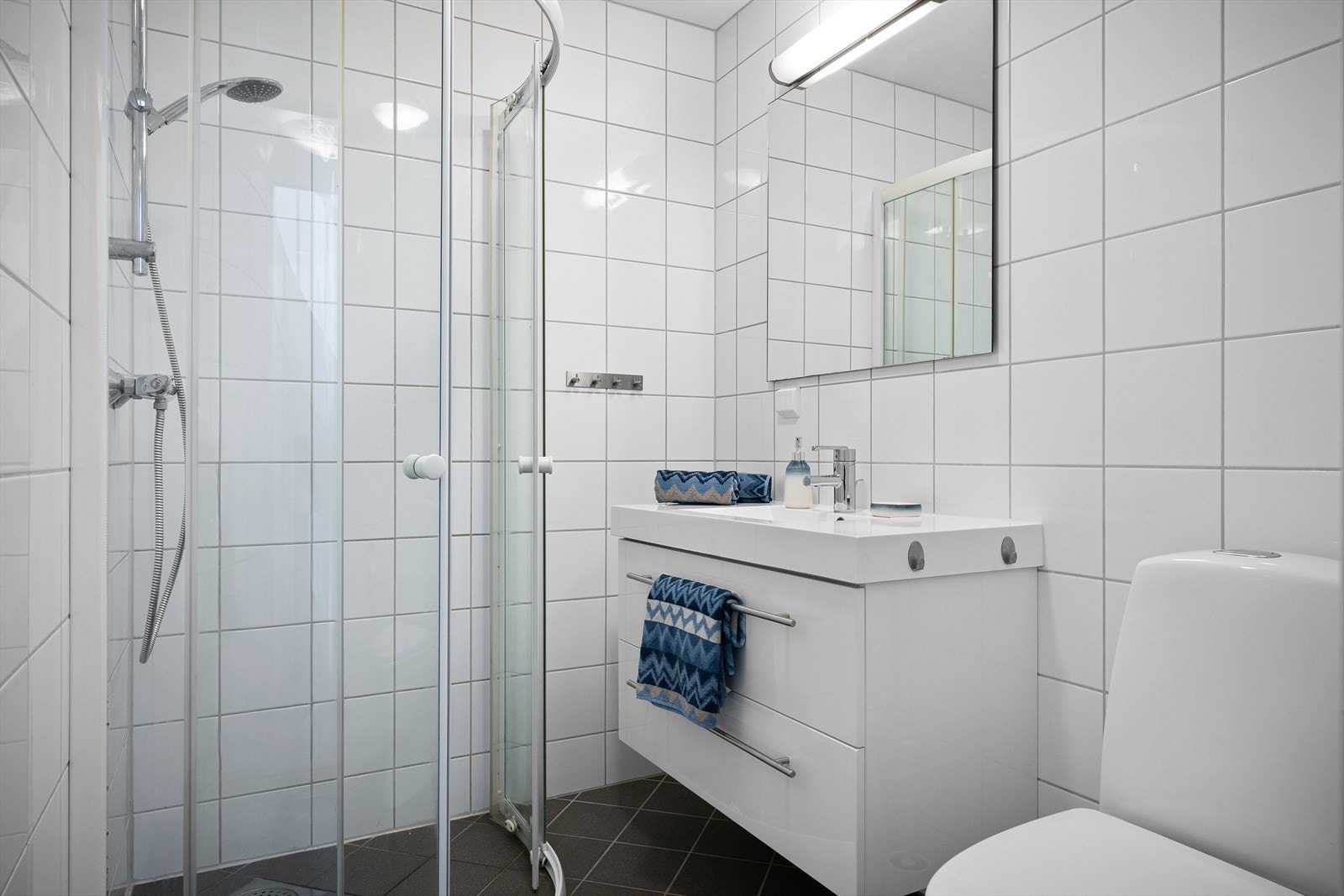 Rommet er utstyrt med en praktisk dusjnisje, toalett og servant med skuffeinnredning. Galleribilde