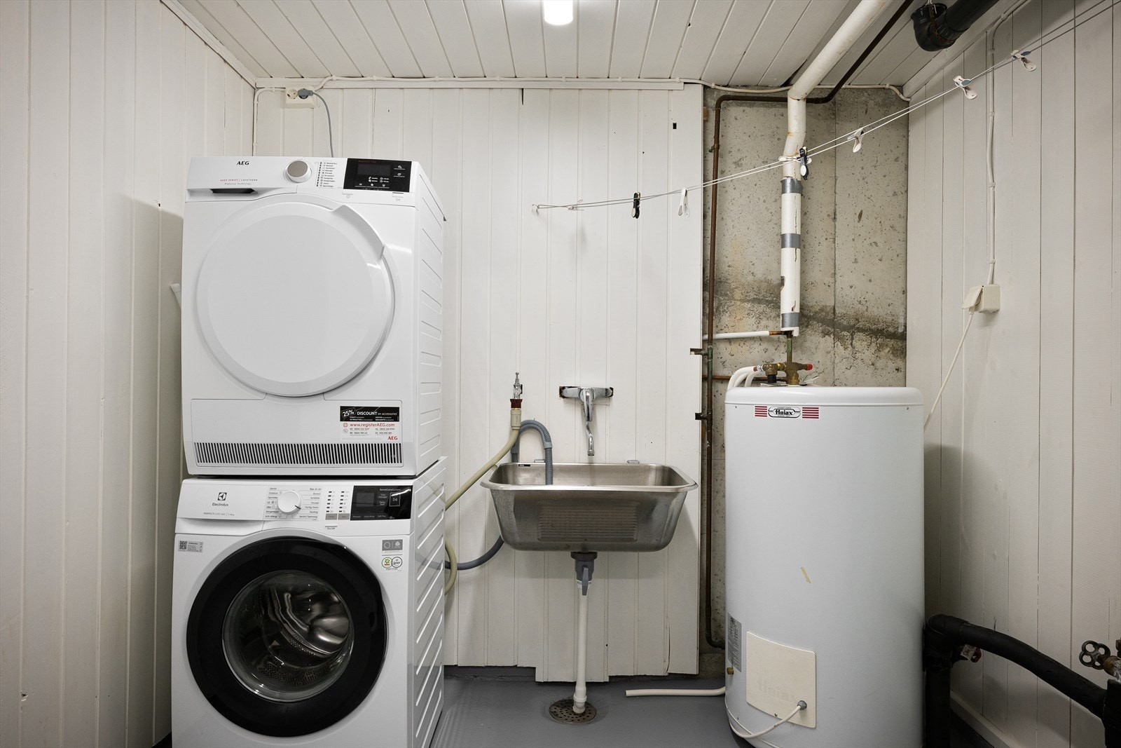 Vaskerom med opplegg for vaskemaskin og tørketrommel, utslagsvask og sluk i gulvet. Galleribilde