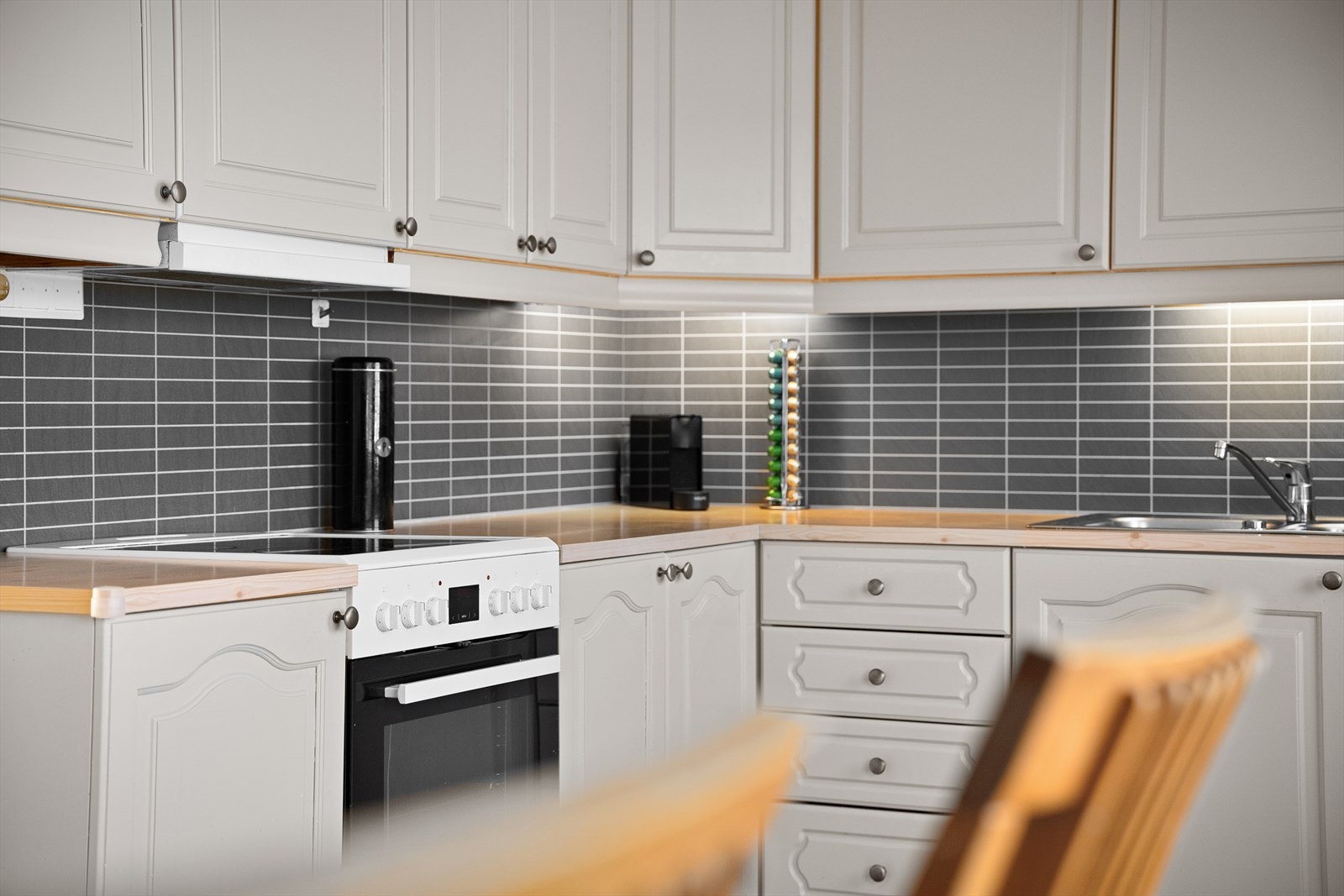 Benkeplaten i laminat har en stålvask med to kummer, og det er Kitchen Wall-plater over benken. Galleribilde