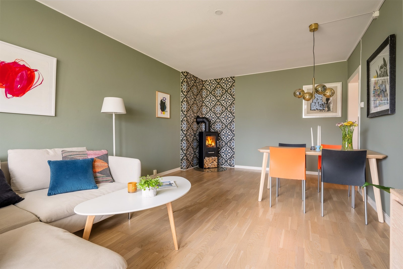 Stuen er malt i en behagelig tone med lekre fliser belagt på vegg bak peisovn, på gulv er det lagt parkett Galleribilde