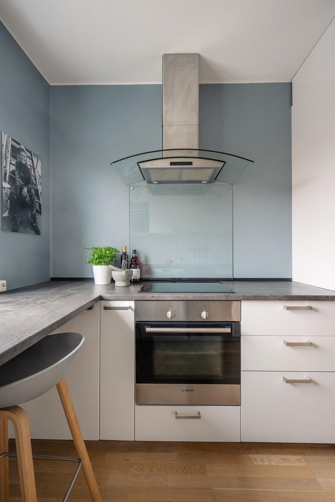 Hvitevarer i form av integrert komfyr og induksjonstopp med ventilator på vegg over, frittstående kjøleskap, fryseskap og oppvaskmaskin. Galleribilde