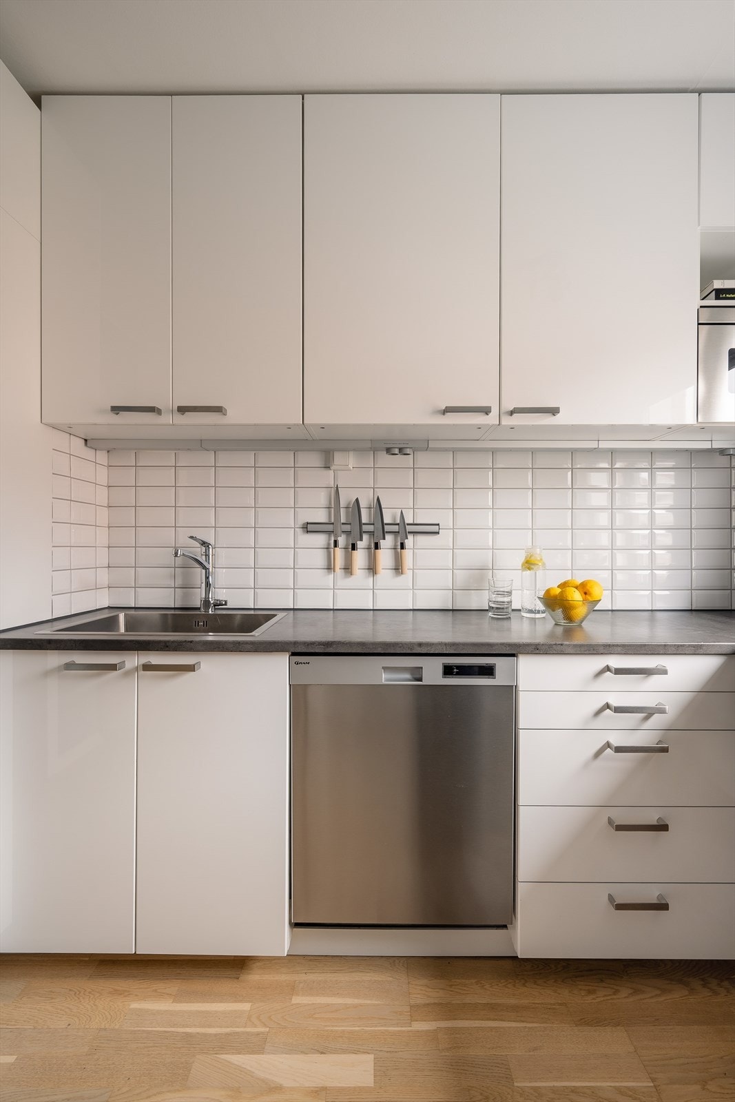 Kjøkkeninnredning fra Ikea med hvite, slette fronter, benkeplater av laminat og nedfelt oppvaskkum i rustfritt stål med ett-greps armatur Galleribilde