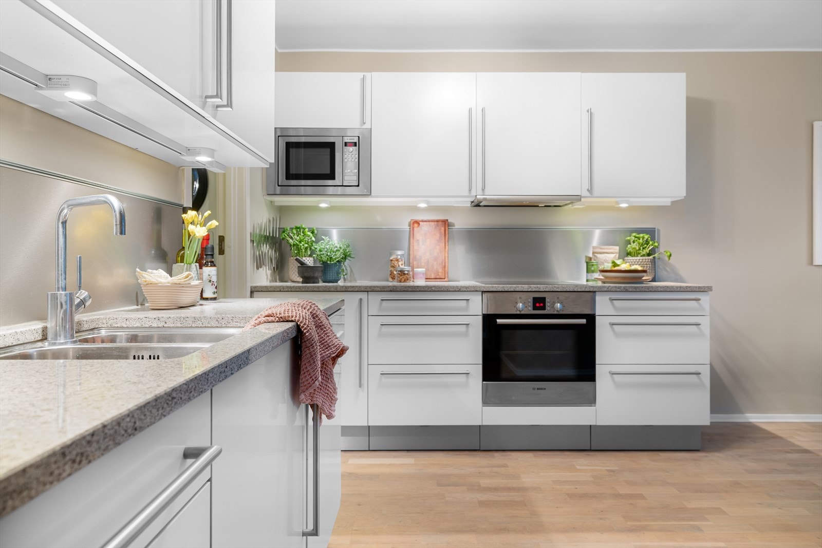 Boligens kjøkken er stilrent med glatte, hvite flater. Galleribilde