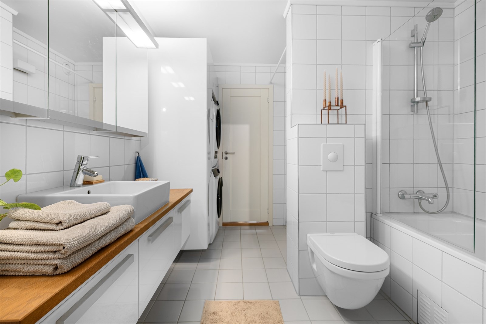 Her er det vaskesøyle, innfliset badekar, benkeskap og veggskap med glatte fronter og heltre benkeplate, samt overskap med speilfronter. Galleribilde