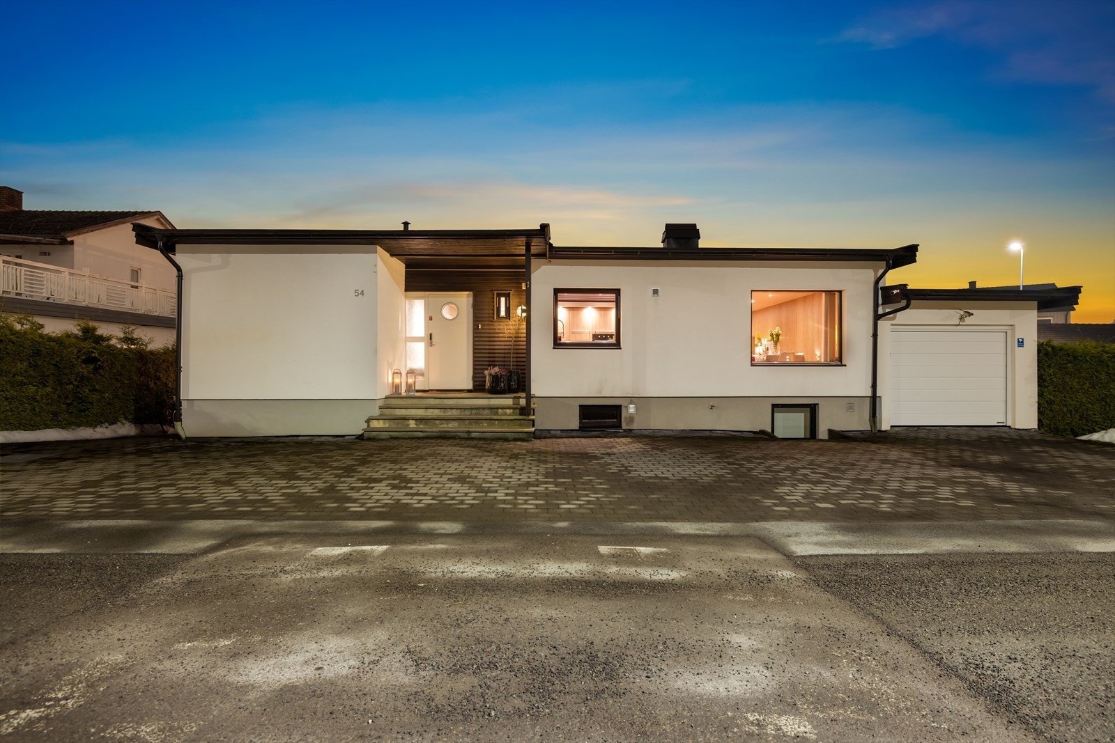 Steinbelagt innkjørsel med flere gode parkeringsmuligheter, samt en enkel garasje ved siden av inngangspartiet. Galleribilde