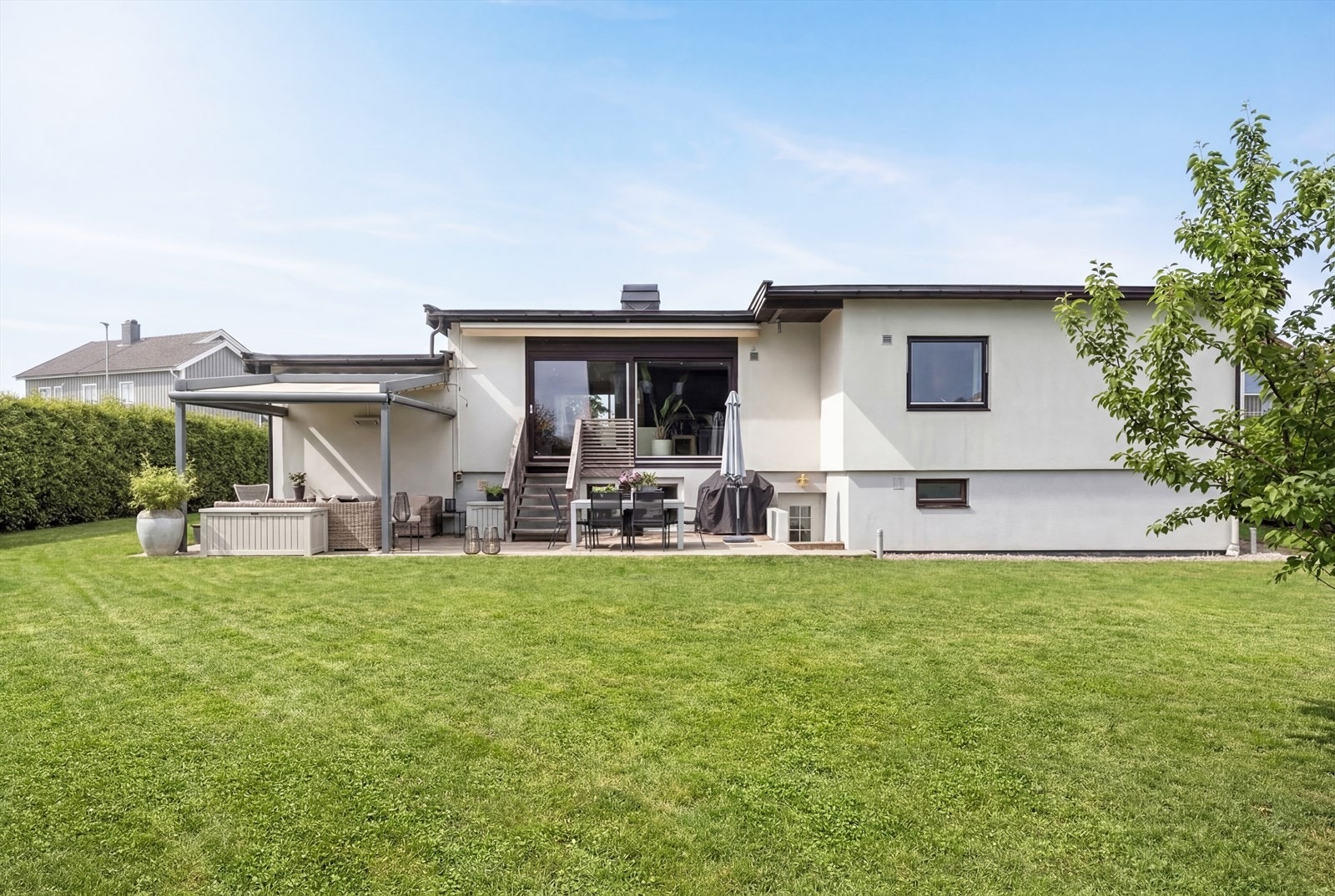 Boligdrømmen i Odalsgata 54A - velkommen til et svært romslig familiehjem på Volla i Lillestrøm. Bildet AI generert for å vise hvordan eiendommen er ut på sommerstid. Galleribilde