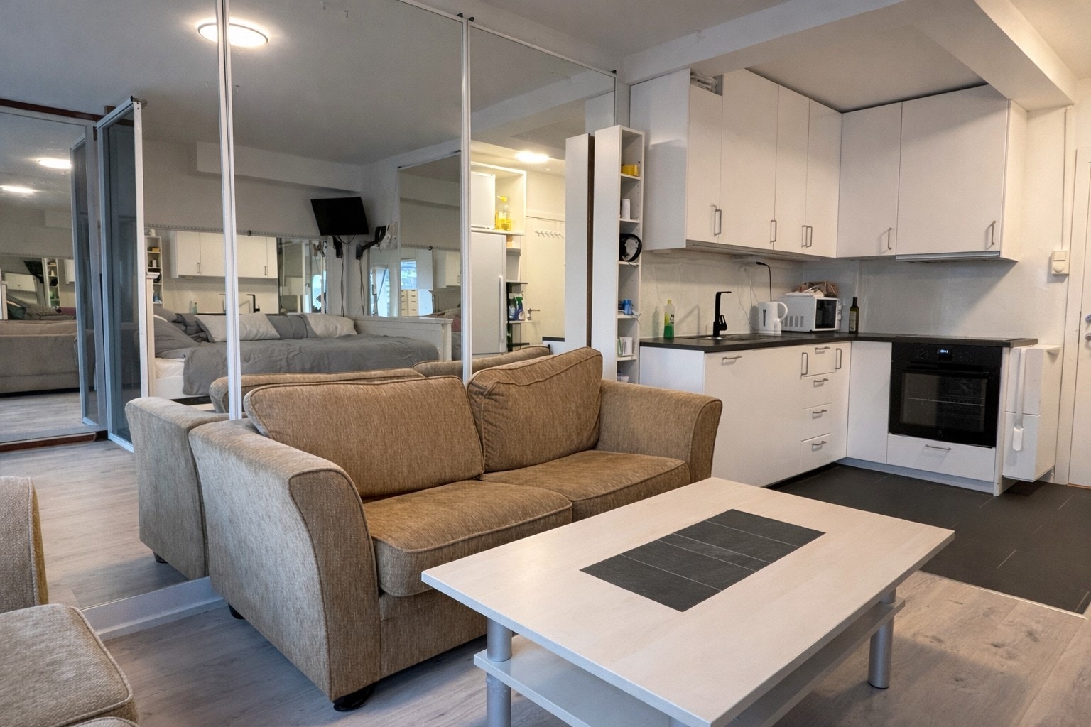 Hybelens oppholdsrom fremstår lyst og innbydende med laminatgulv og lysmalte vegger. Galleribilde