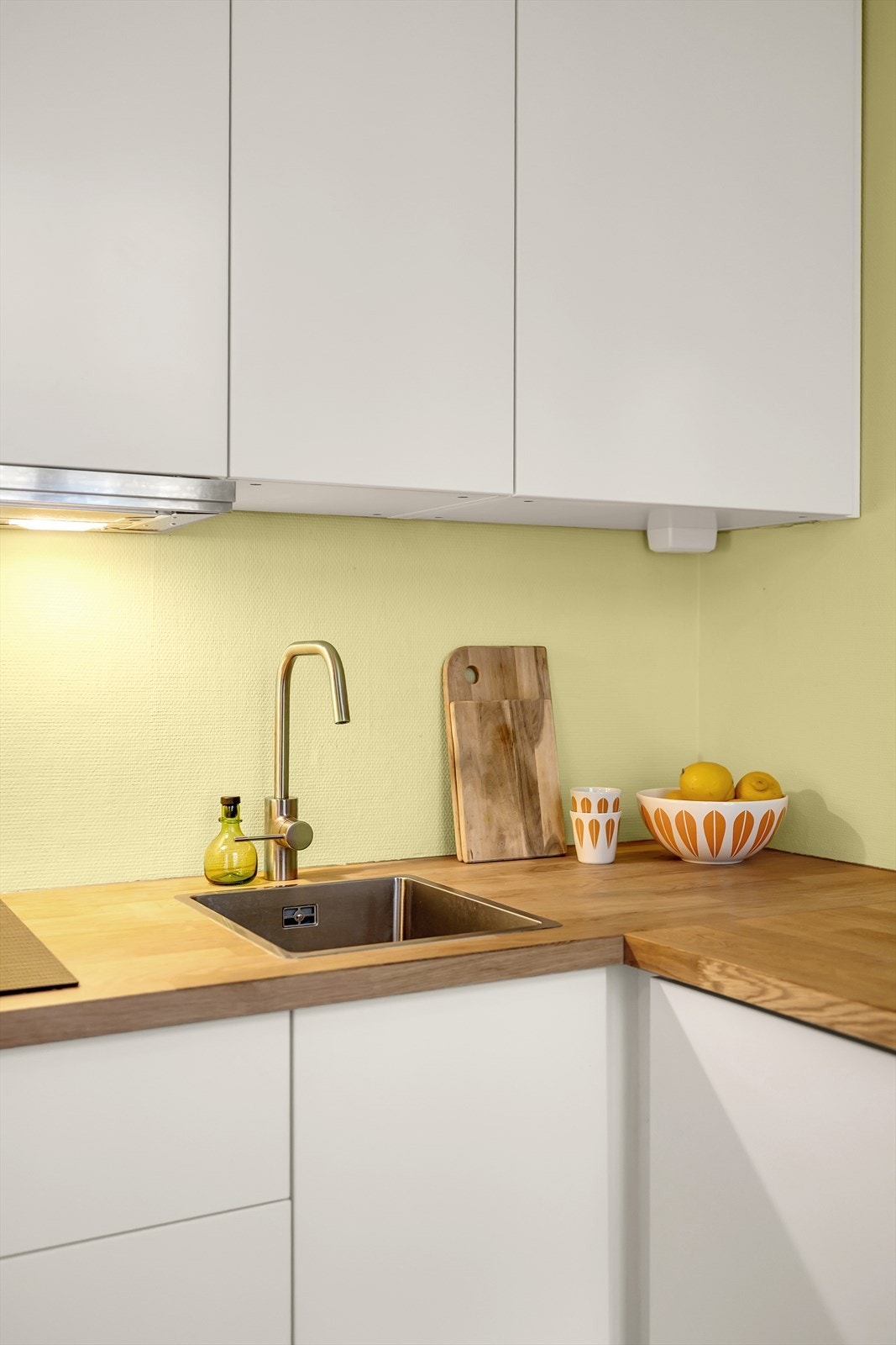 Overskap med kjøkkenventilator med kullfilter. Varmtvannsbereder plassert under kjøkkenbenken. Galleribilde