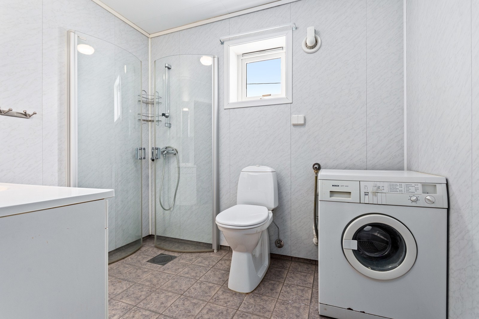 Badet har flislagt golv med varmekablar og baderomsplater på vegger. Galleribilde