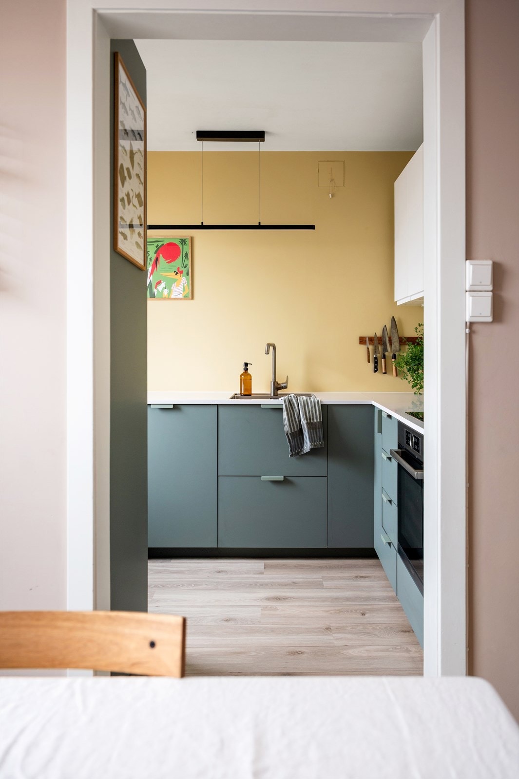 Stilrent og moderne kjøkken fra 2021 med glatte, grønne fronter som skaper et friskt uttrykk i kombinasjon med lune, gule veggflater. Galleribilde