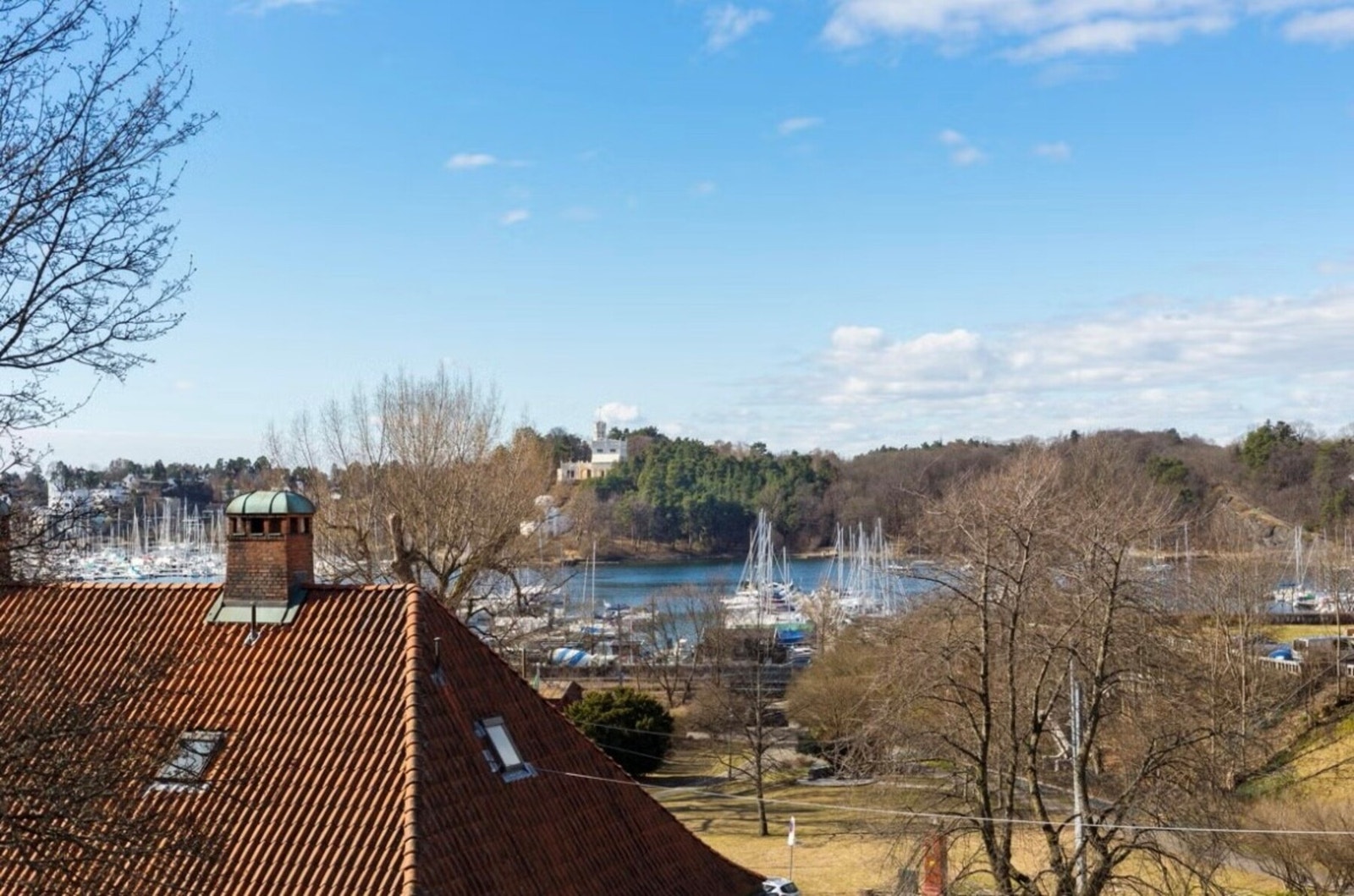 Oversiktsbilde fra en annen leilighet i blokken som viser de flotte næromgivelsene, med nærhet til grøntarealer og fjorden. Galleribilde