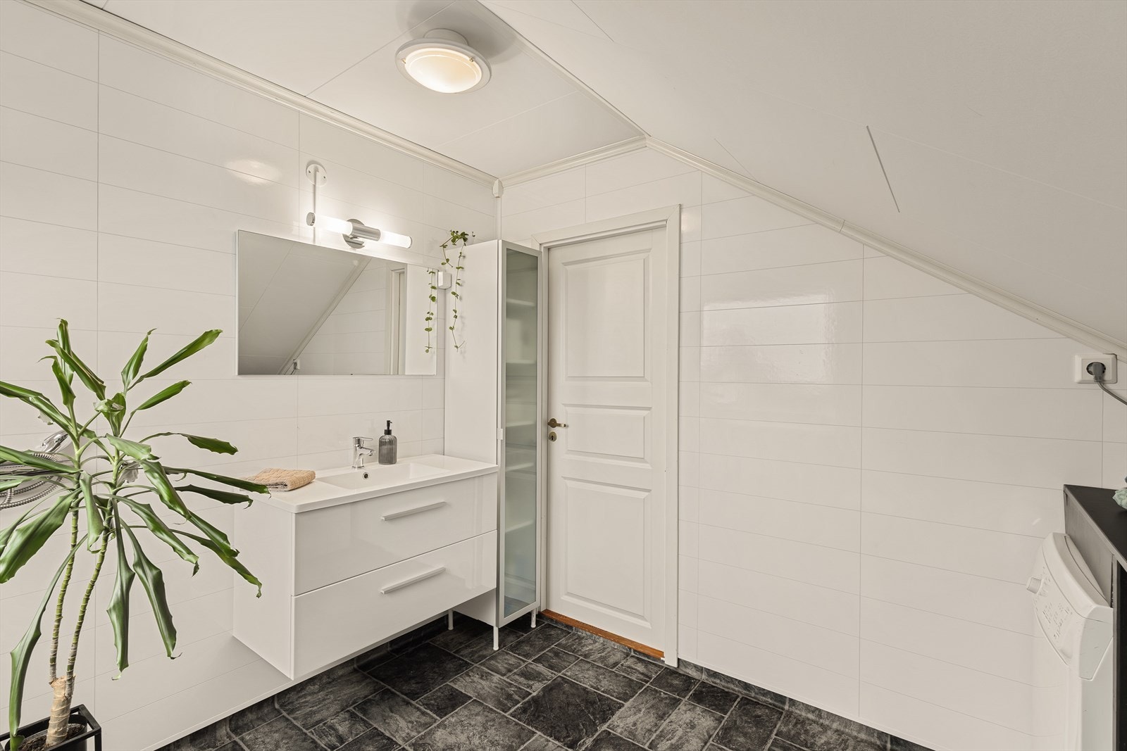 Badet inneholder servant med underskuffer, høyskap, toalett, opplegg for dusj og opplegg for vaskemaskin. Galleribilde