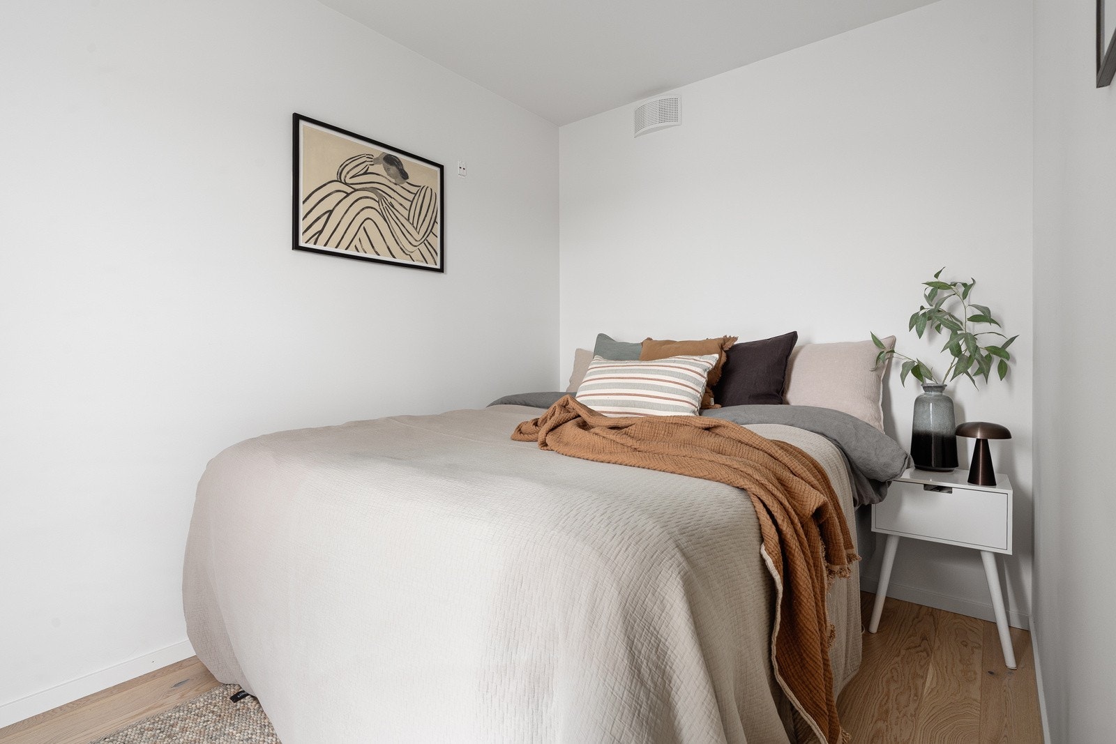 Leilighetens soverom framstår romslig, med god plass for stor seng og tilhørende nattbord. Galleribilde