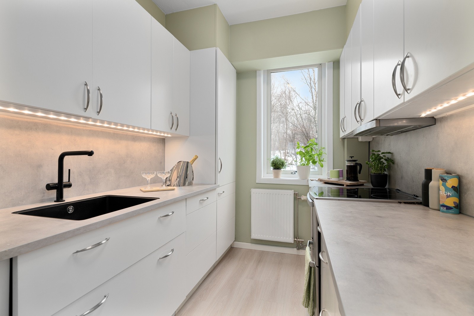 Kjøkkeninnredningen har glatte fronter og benkeplate i laminat med nedfelt oppvaskkum, samt belysning over benkeplaten. Galleribilde