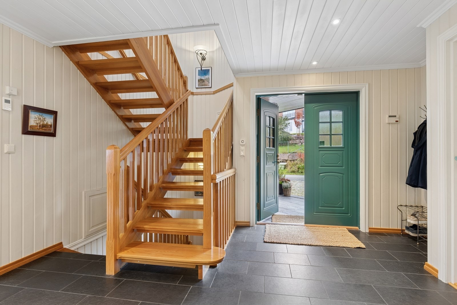 Innbydende entré med flislagt trapp og plass til garderobe Galleribilde