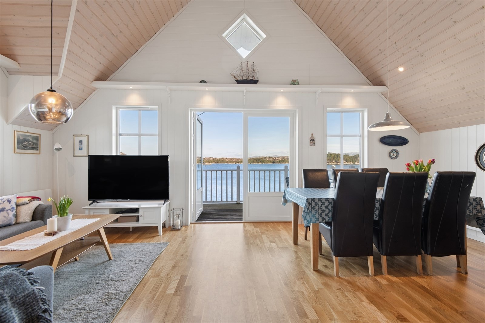 Den åpne løsningen mellom stue og kjøkken og den høye takhimlingen skaper et luftig og sosialt allrom. Galleribilde