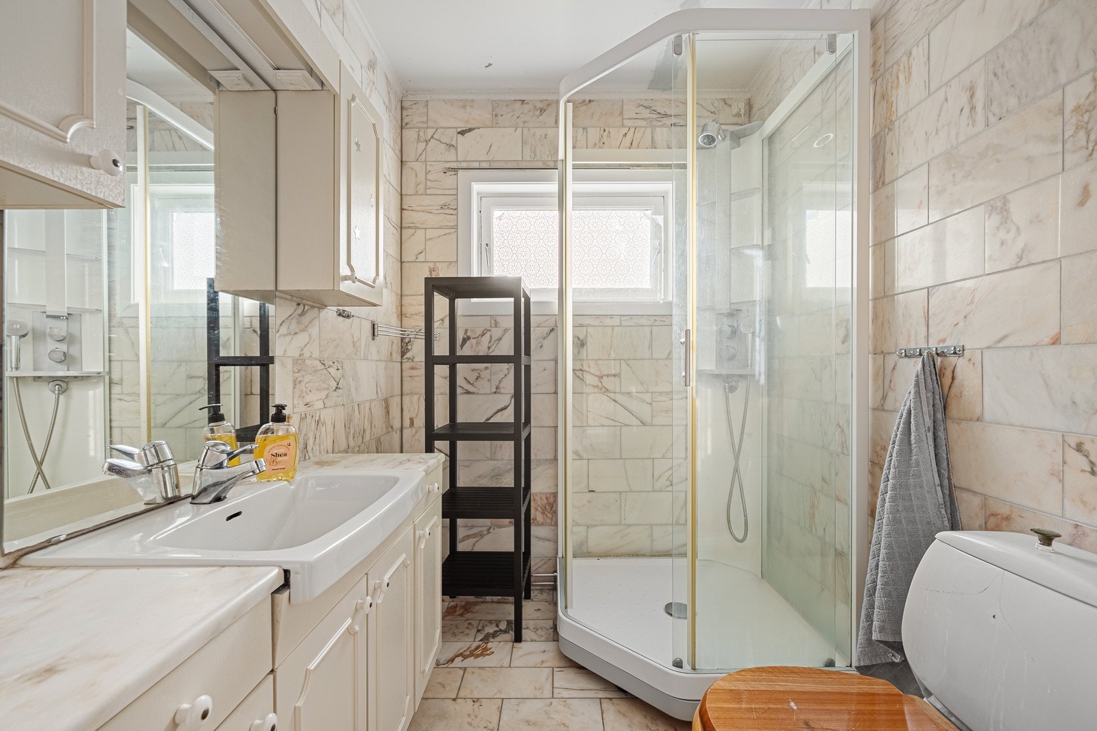 Badet har marmorflis på gulv- og veggflater Galleribilde