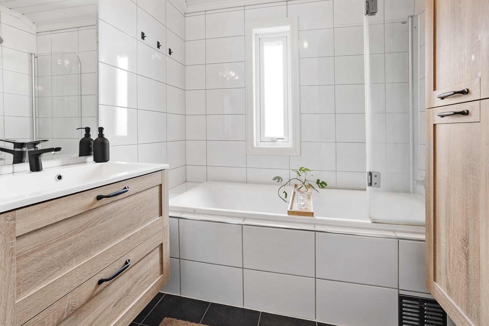 Badet har badekar, baderomsinnredning og vegghengt toalett Galleribilde