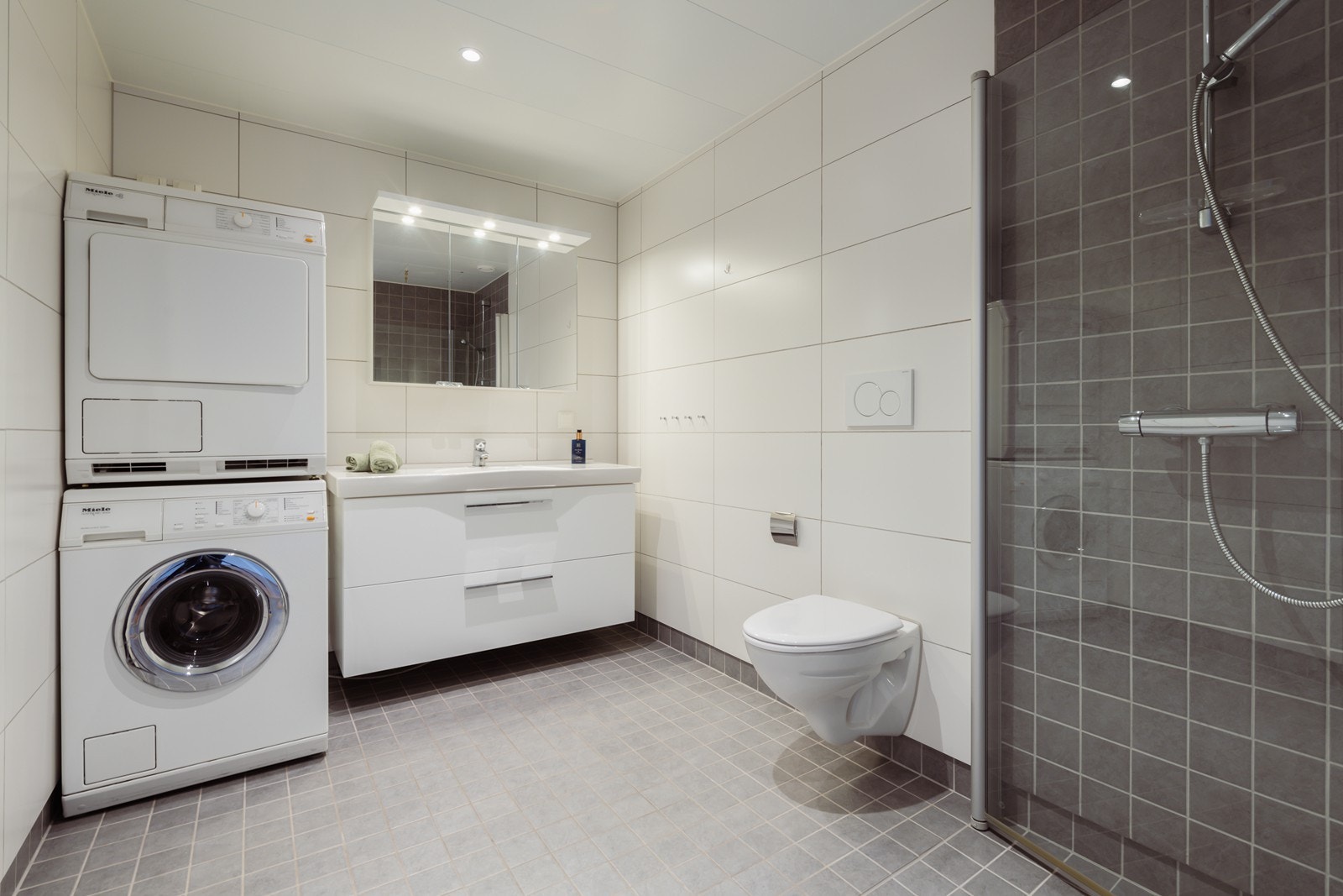 Lekkert, flislagt bad/vaskerom. Galleribilde