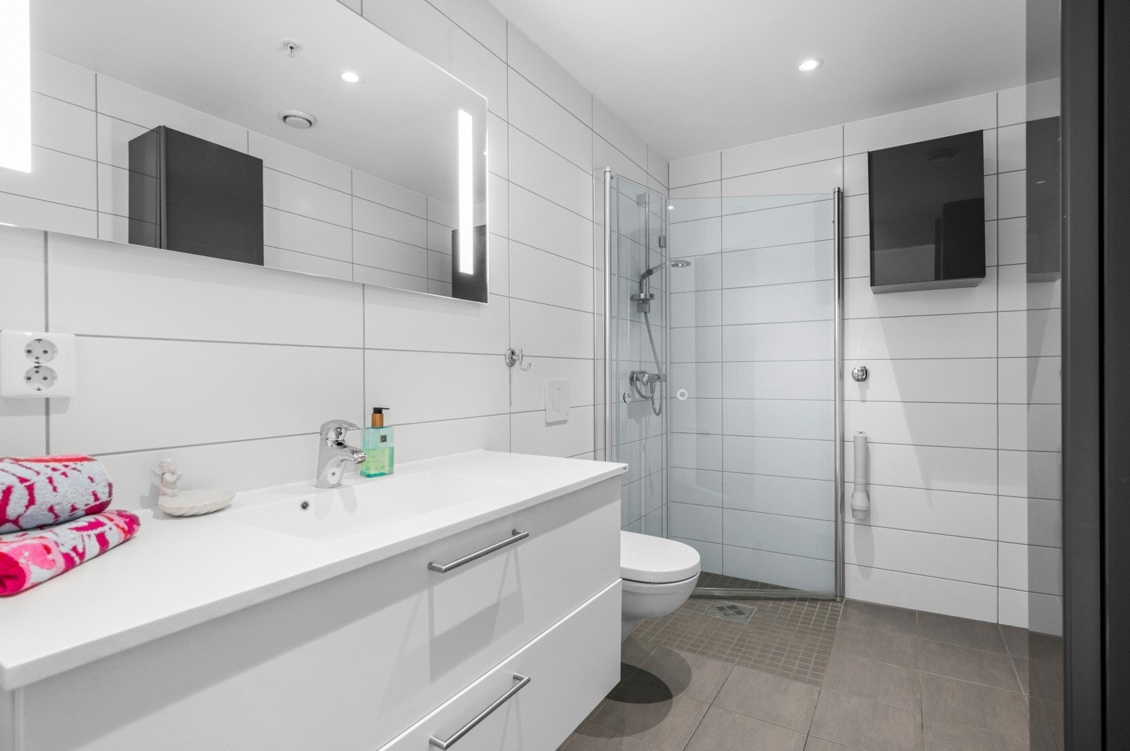 Badet er 5 kvm. og har flis på gulv og vegg. God plass til vaskmaskin og vegghengt WC. Innfellbare dusjdører og god lagringsplass i skuffer. TG 1 i tilstandsrapport. Galleribilde