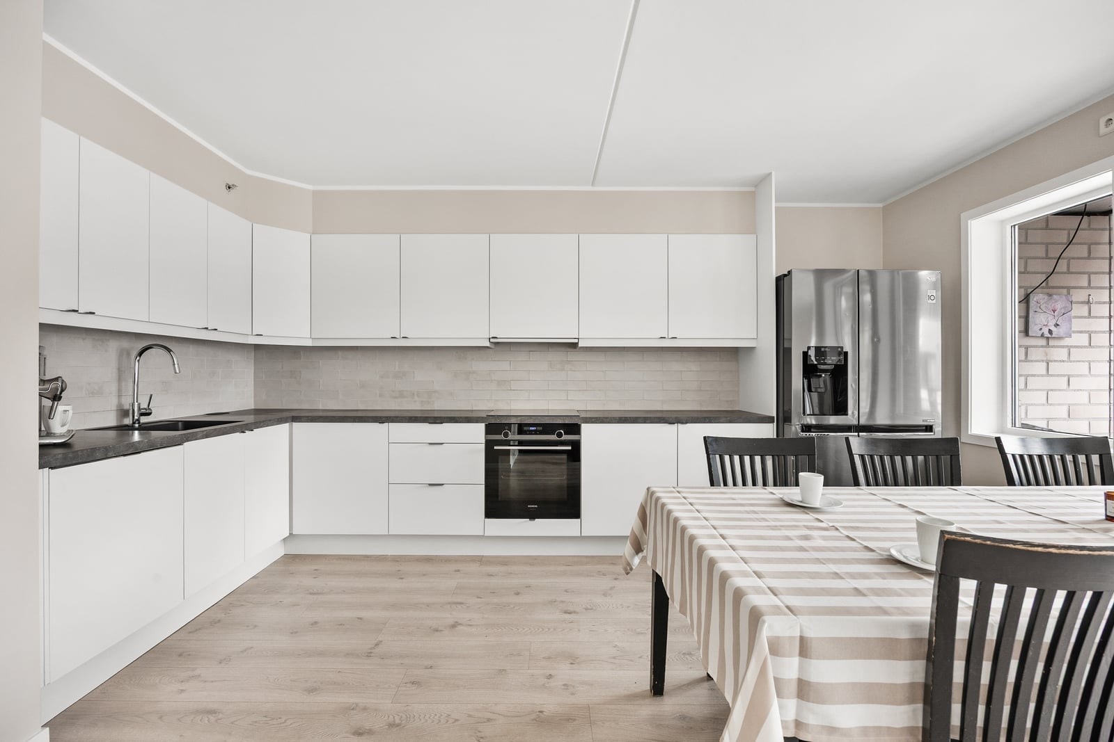 Fint kjøkken med mye skap- og benkeplass. Kjøkkeninnredningen strekker seg langs to vegger. Galleribilde