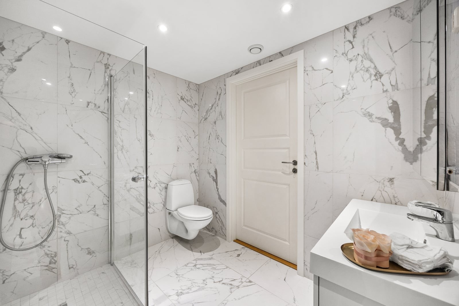 Badet er innredet med servant i baderomsinnredning, dusjhjørne med glassvegger og vegghengt toalett. Galleribilde