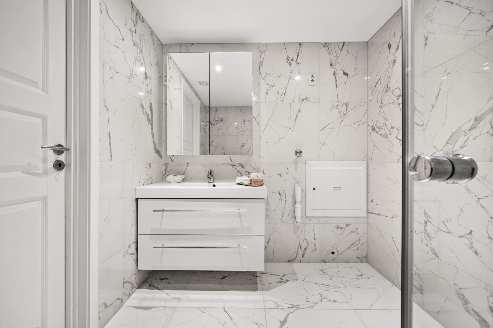 Servant i baderomsinnredning med skuffer, speilskap over og opplegg for vaskemaskin. Galleribilde