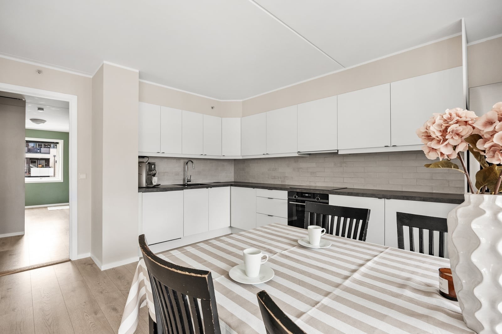 Kjøkkeninnredningen har stilrene og hvite, glatte fronter, samt laminert benkeplate. Galleribilde