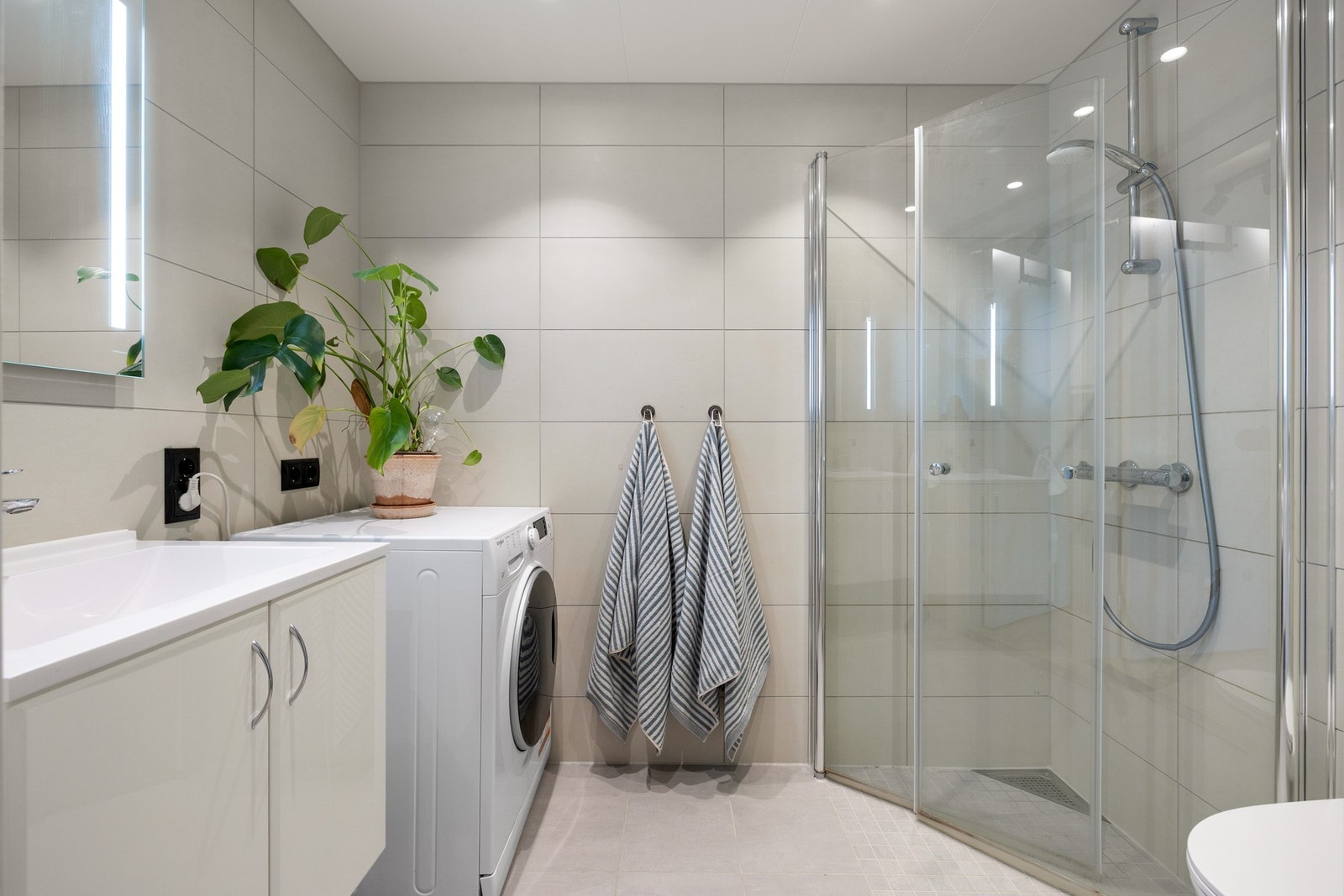 Baderommet med fliser på gulv og vegg holder en moderne standard og er vurdert til tilstandsgrad 0/1 av takstmann. Galleribilde