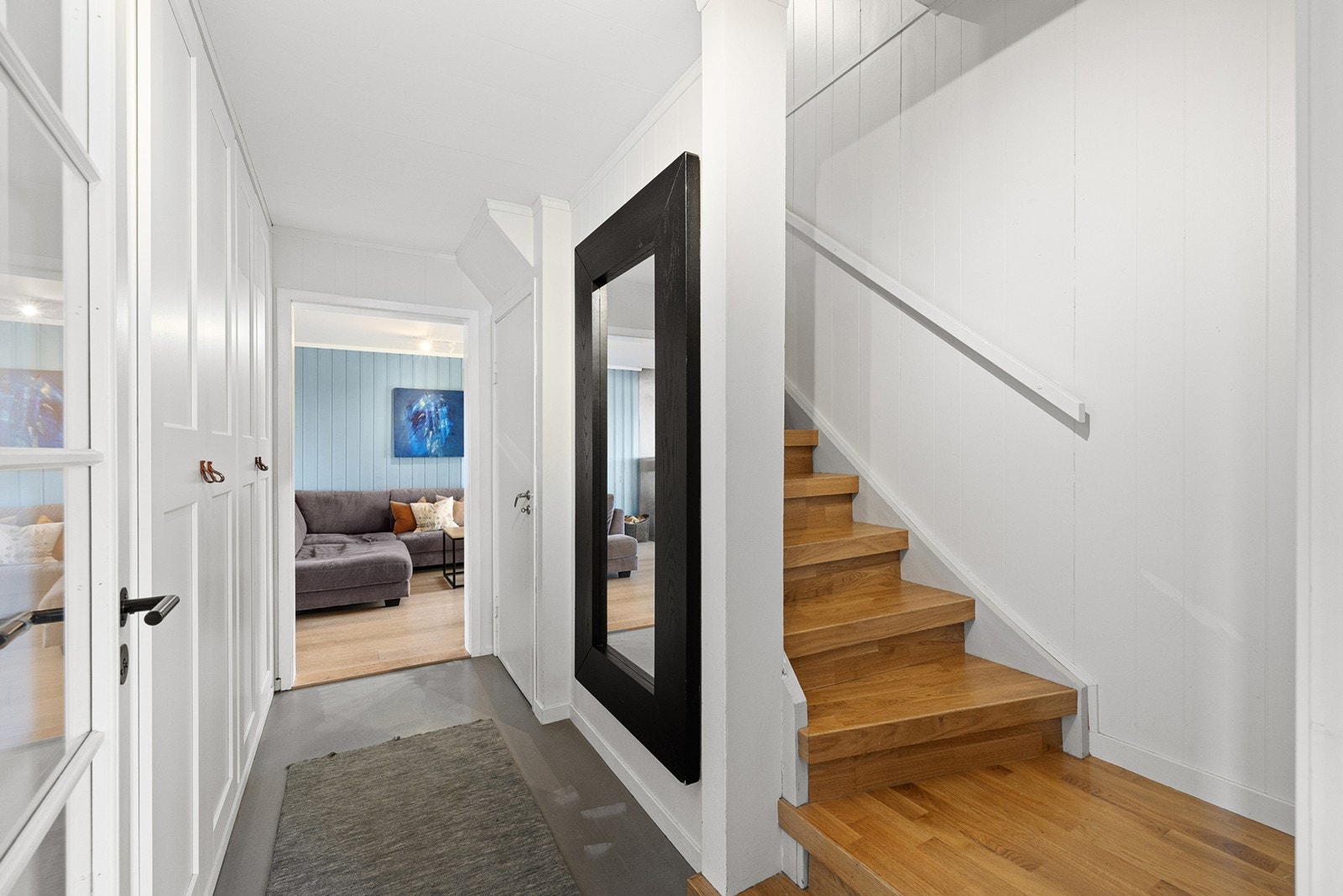 Fra entreen leder gangen videre inn i boligen med pene overflater og en flott trapp opp til andre etasje. Her finner du også et praktisk garderobeskap som gir rikelig med lagringsplass. Galleribilde