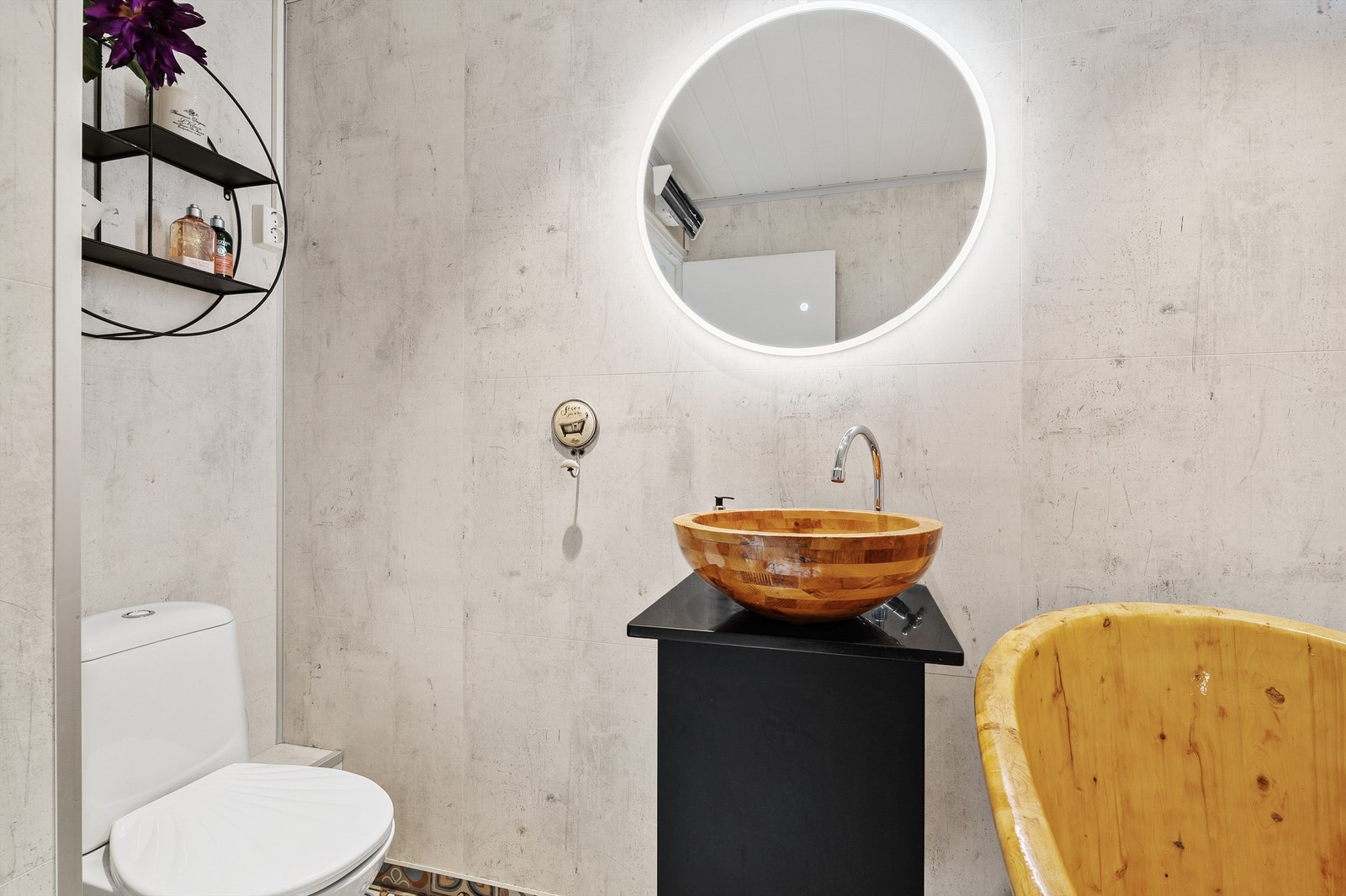 Badet er innredet med badekar, gulvstående toalett, baderomsinnredning og speil med integrert lys. Galleribilde