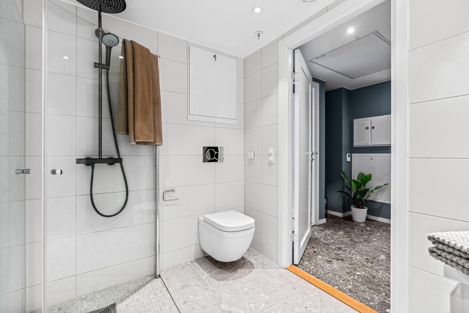 Vegghengt toalett, dusjhjørne med regndusj, hånddusj og svingbare glassdører. Galleribilde