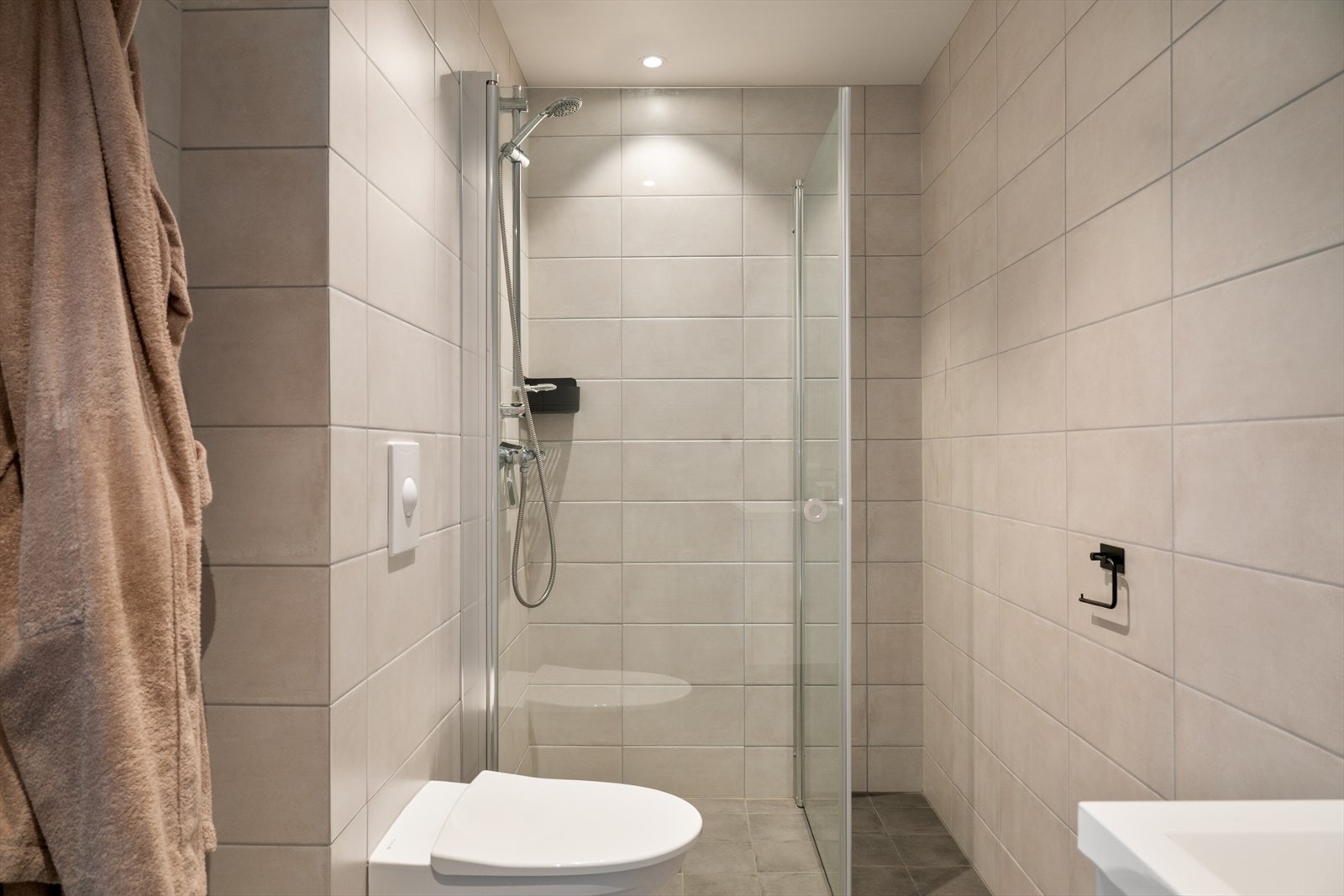 Leilighetens andre bad med tilkomst fra soverom. Badet er innredet med vask i seksjon, speil med belysning, veggehengt toalett og foldbare dusjdører i glass. Galleribilde