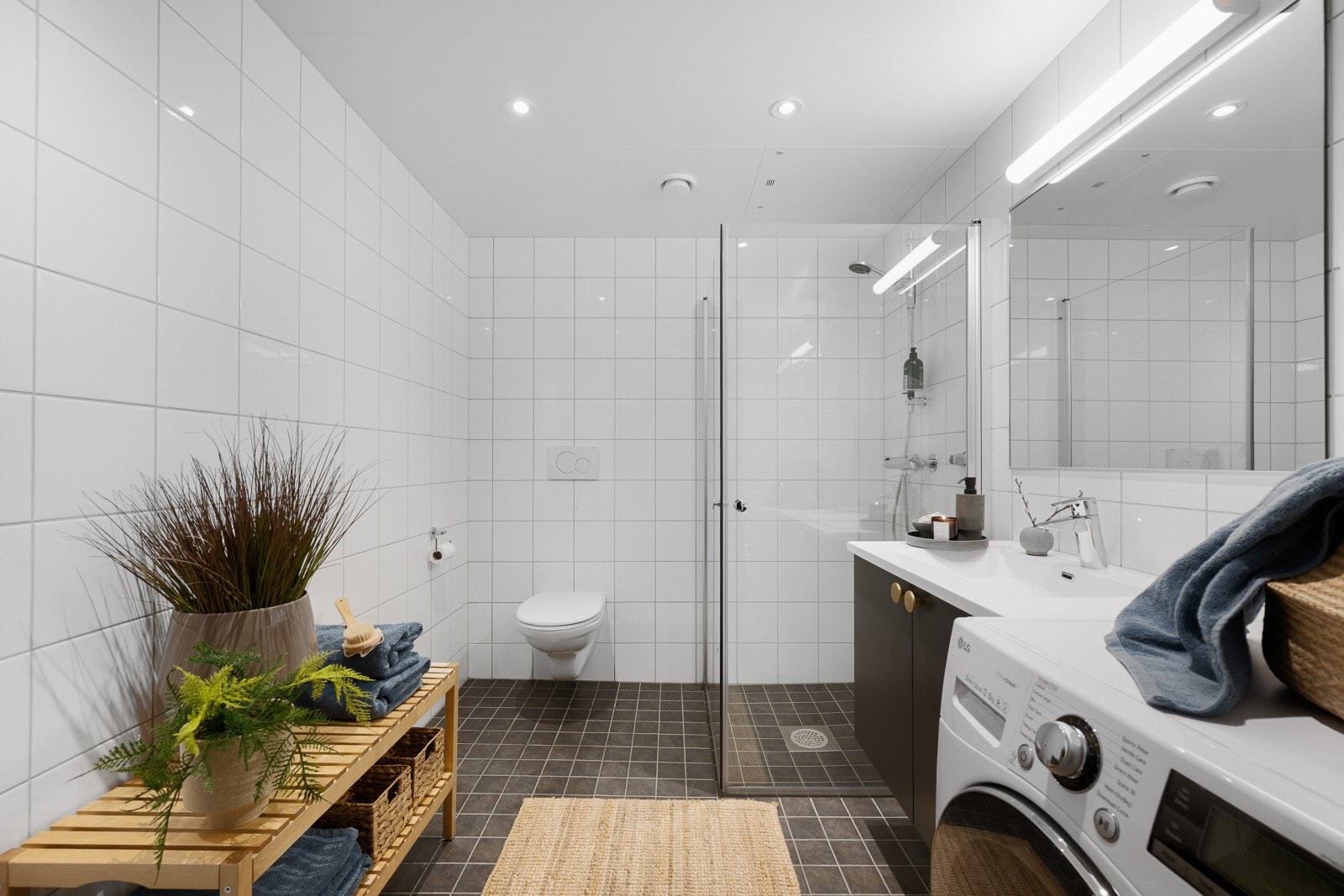 Leiligheten har et pent bad med grå fliser på gulv og hvite fliser på veggene. Galleribilde