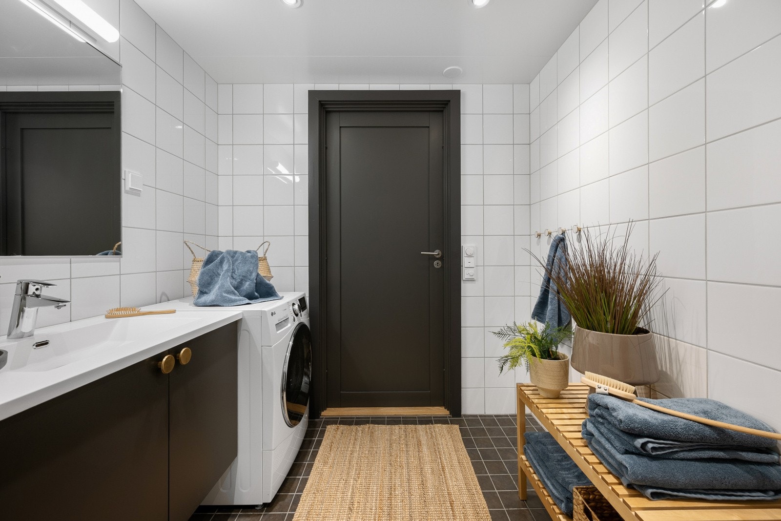 Badet er moderne utstyrt med en sort servantinnredning, speil med lys over, dusjhjørne, toalett og opplegg for vaskemaskin. Galleribilde