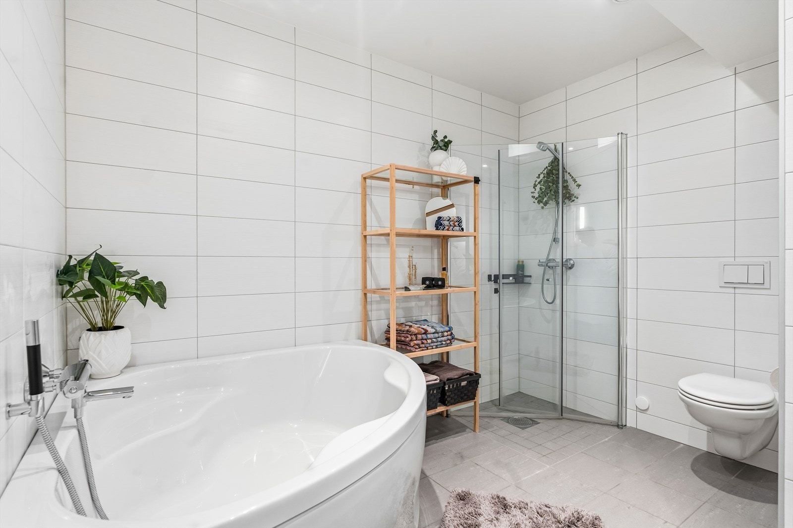 Flislagt, delikat baderom med dusjhjørne, badekar og vegghengt toalett. Galleribilde