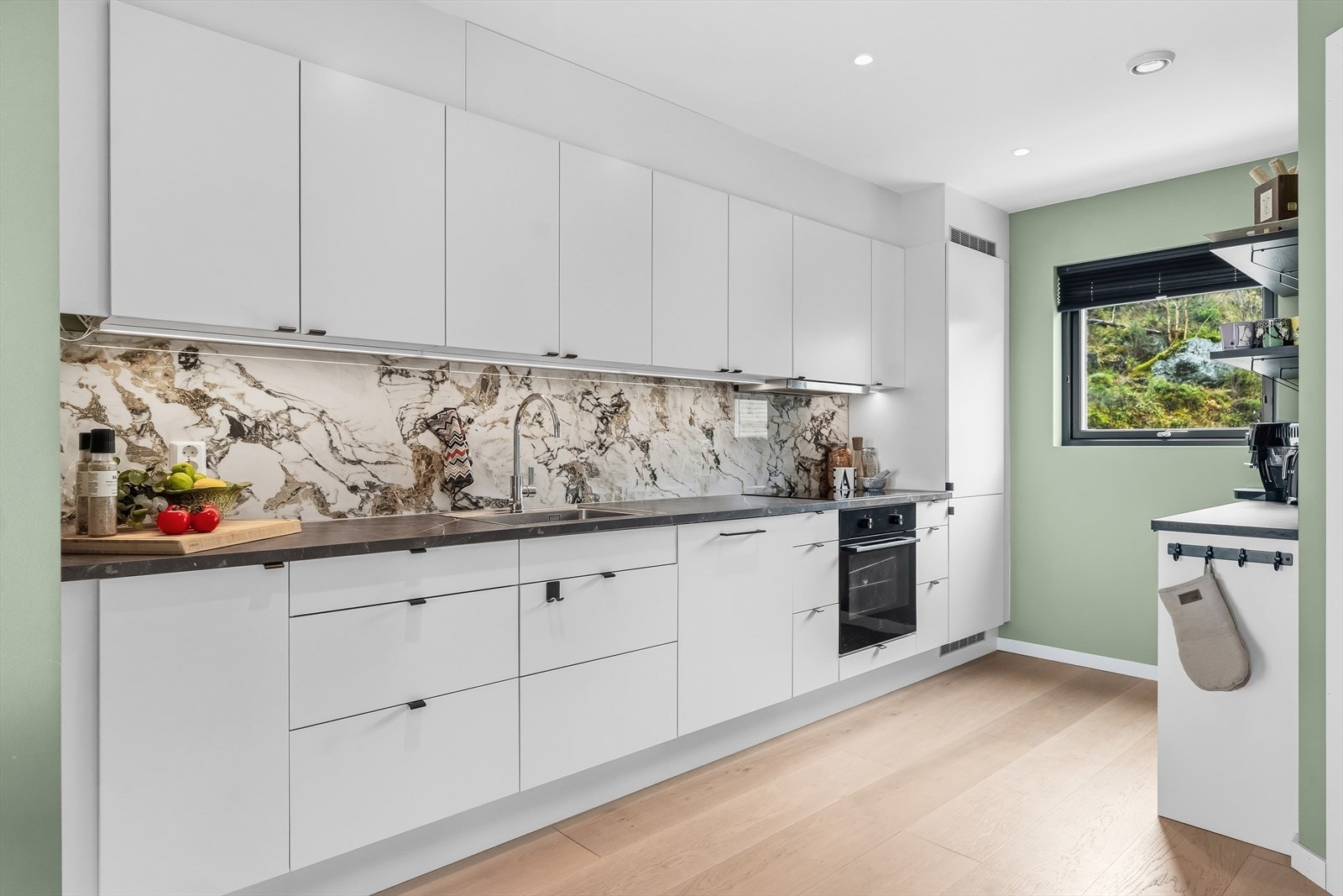 Lekkert og tidløst kjøkken med lyse, glatte fronter og integrerte hvitevarer. Galleribilde