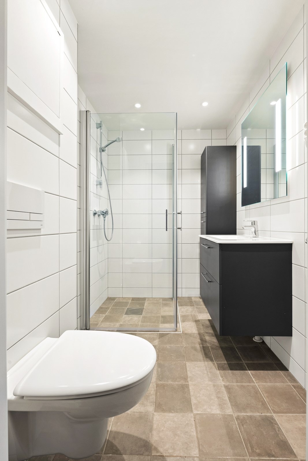 Badet er innredet med heldekkende nedfelt servant med rom for oppbevaring skuffer, speil, toalett og dusjhjørne. Galleribilde