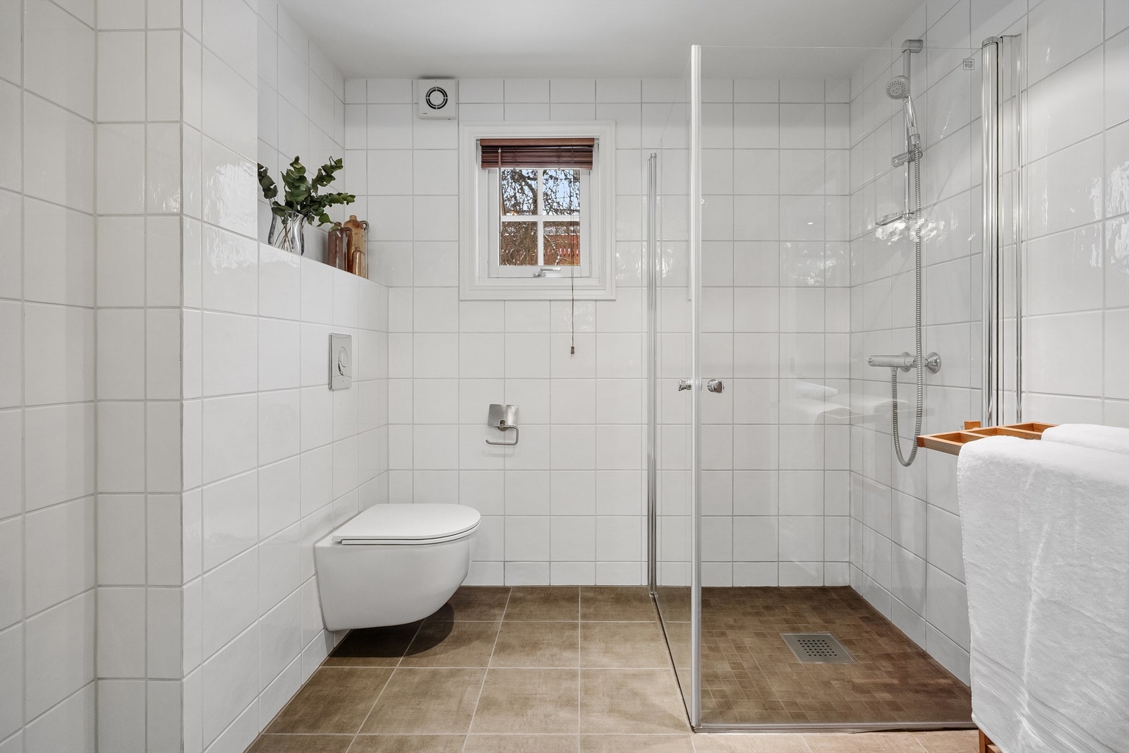 Rommet har et vegghengt toalett og et romslig dusjhjørne med svingbare glassdører. Galleribilde