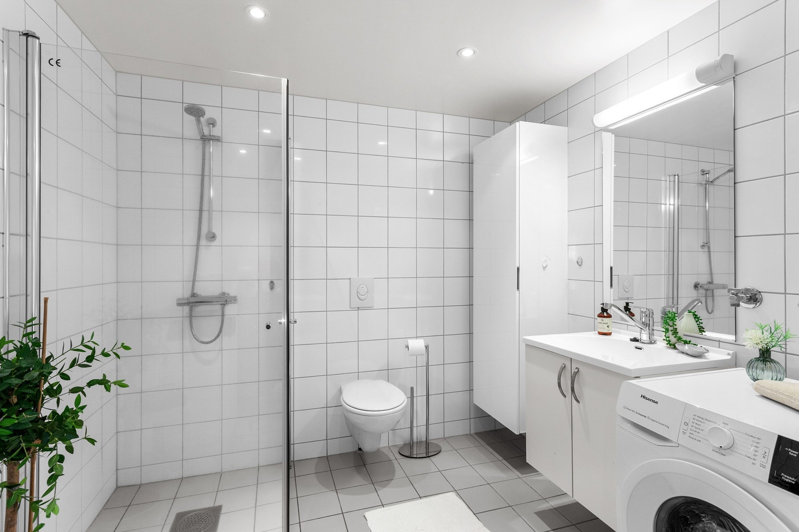 Flislagt bad med gulvvarme. Himling med downlights. Vegghengt servantinnredning med ovenpåliggende servant. Dusjhjørne med dører i glass. Galleribilde