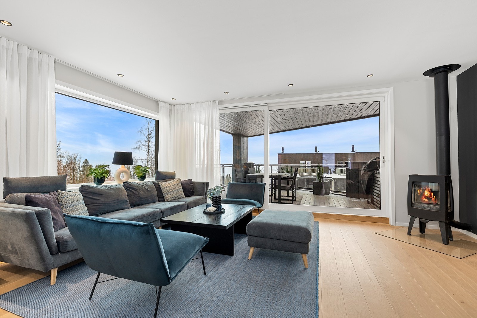 En elegant og varmende vedovn er fint plassert i hjørne av stuen. Galleribilde