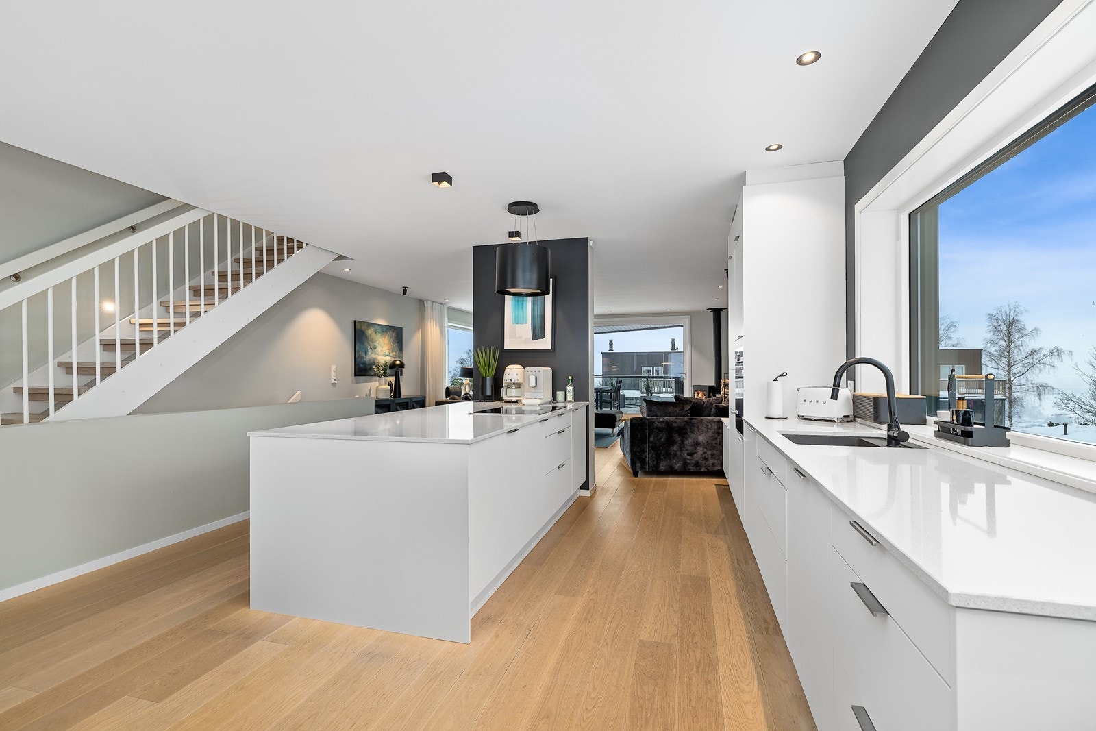 Delikat kjøkkeninnredning med slette, hvite fronter og benkeplate av stein med underlimt vask. Galleribilde