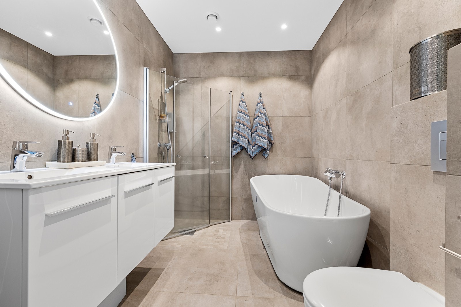 Hovedbadet i 2.etasje fremstår eksklusivt med store fliser i en varm, naturlig tone. Galleribilde