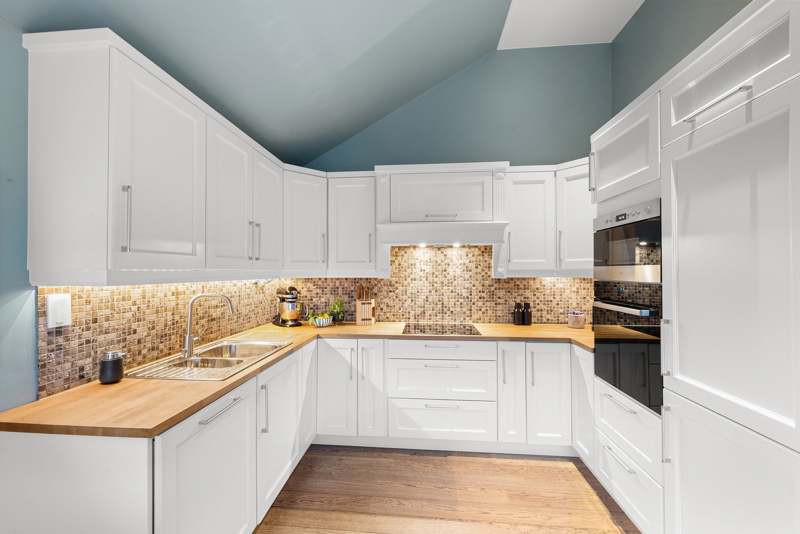 Hvit, stilren innredning med integrerte hvitevarer. Galleribilde