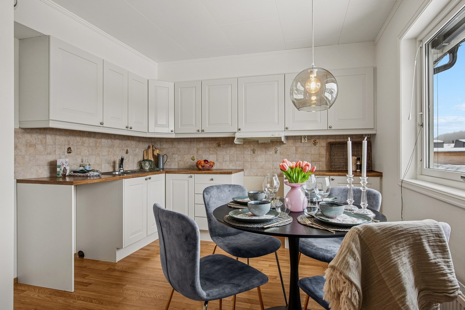 Kjøkkenet har en tidløs og moderne innredning med hvite, profilerte fronter og laminert benkeplate med nedfelt kjøkkenkum. Galleribilde