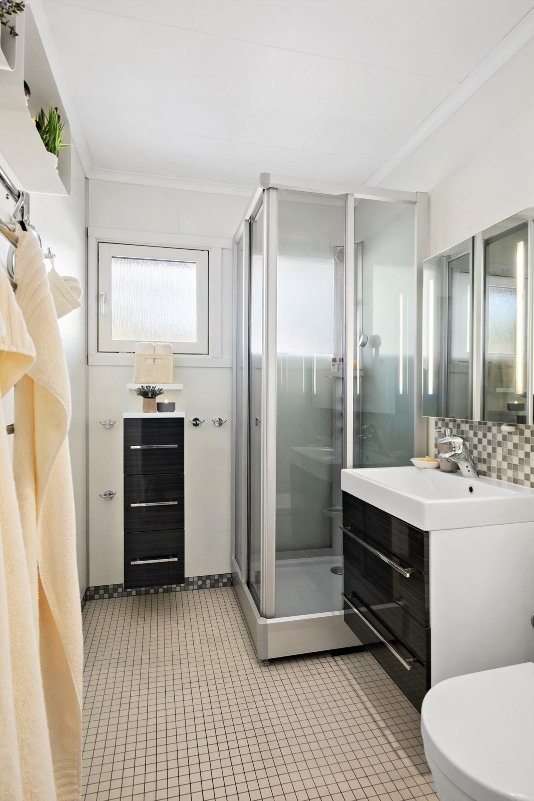 Badet fremstår praktisk utformet med flislagt gulv og dusjsone med baderomsplater på vegg. Galleribilde