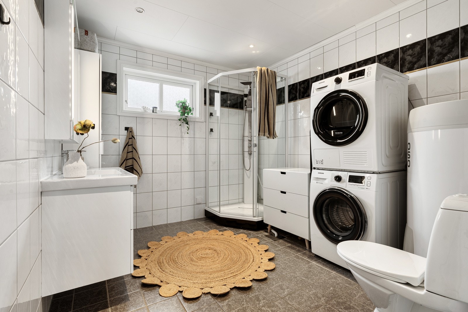 Romslig baderom som er flislagt. Opplegg for vaskemaskin og tørketrommel. Galleribilde