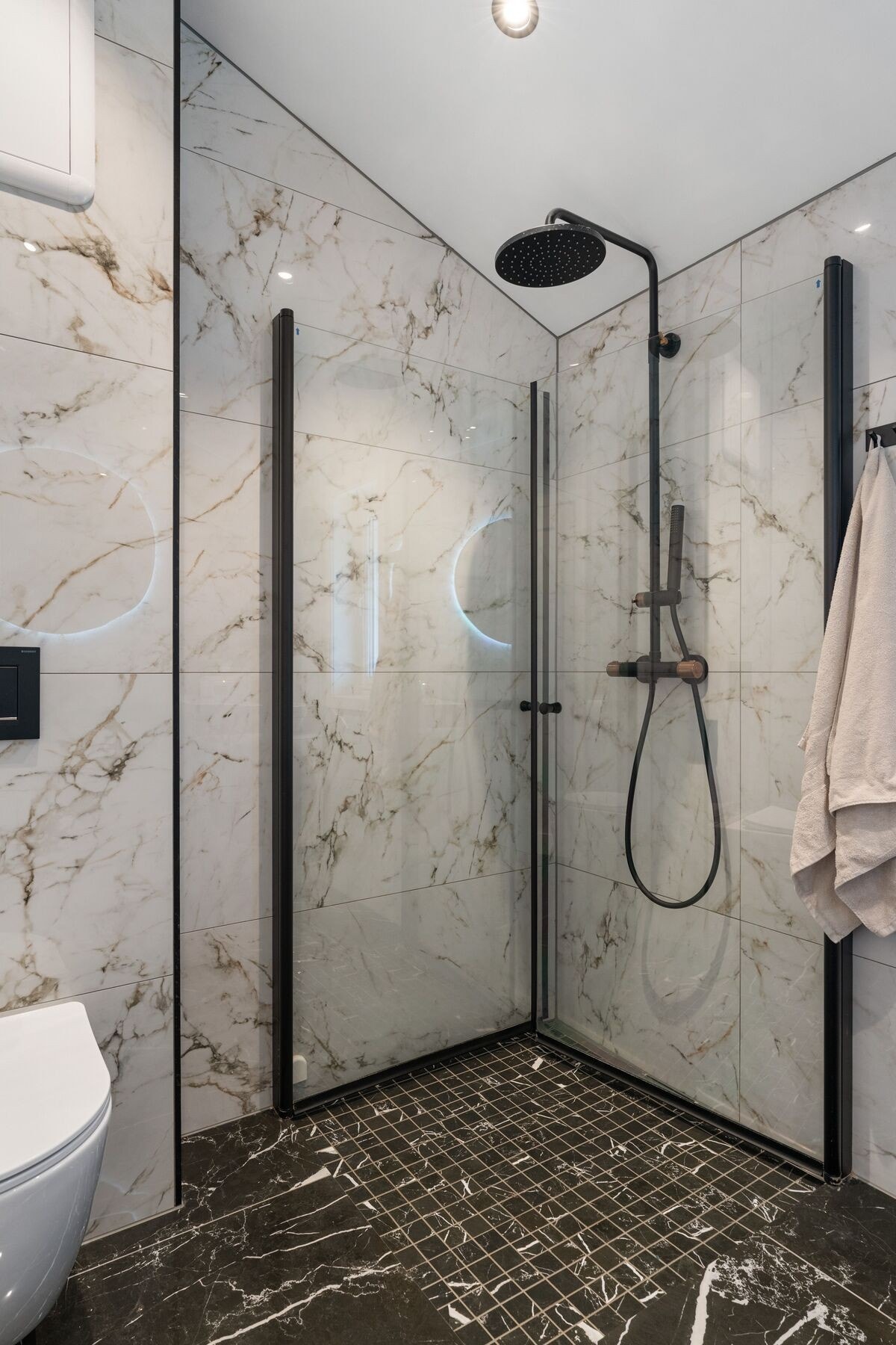 Badet er utstyrt med servant med innredning, speil med lys, dusjhjørne med innfellbare dusjdører, vegghengt toalett og opplegg for vaskemaskin. Galleribilde