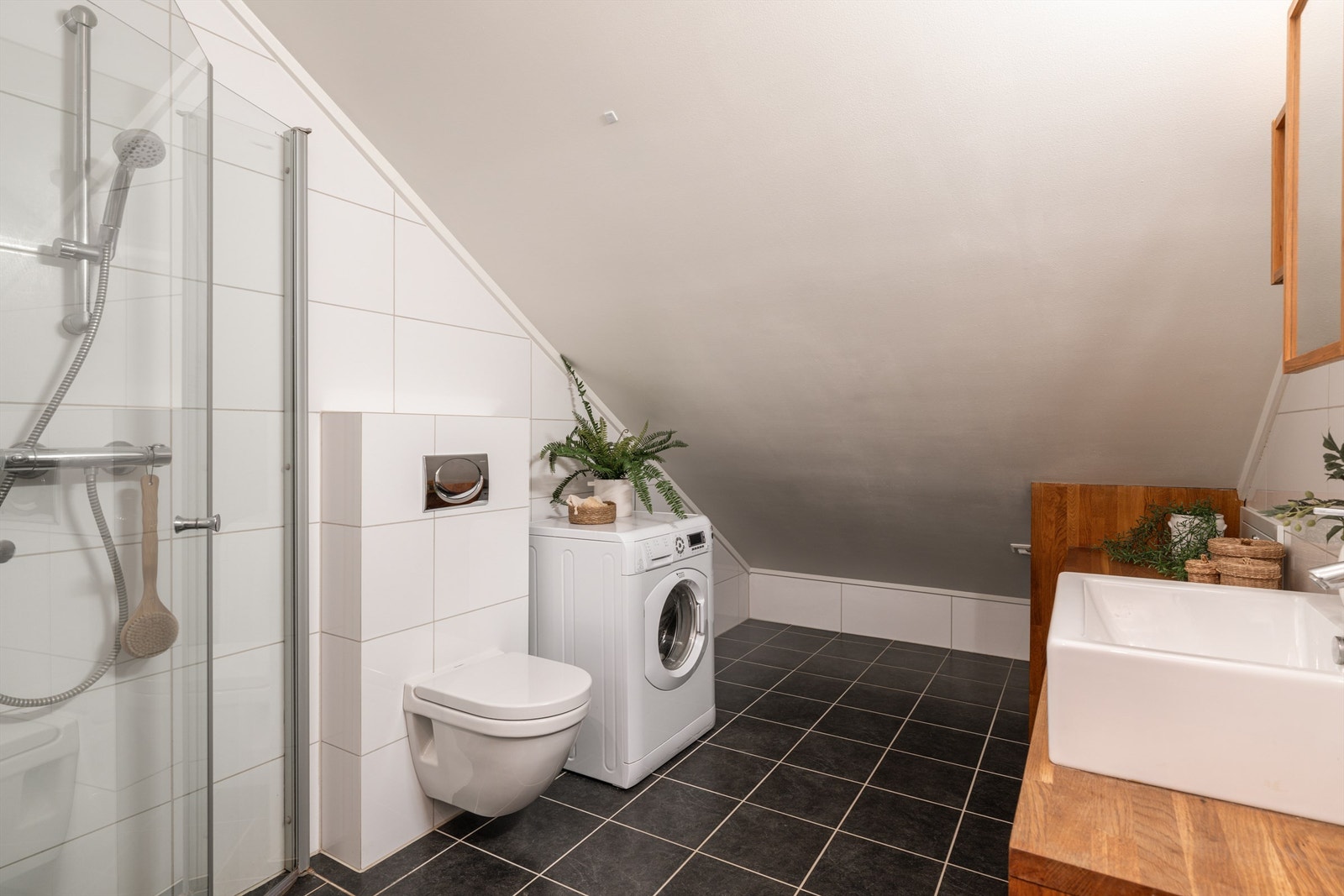 Her er det dusjhjørne med glassdører, vegghengt toalett og opplegg for vaskemaskin. Galleribilde